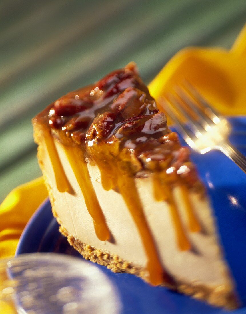 A slice of cheesecake with pecans and caramel sauce