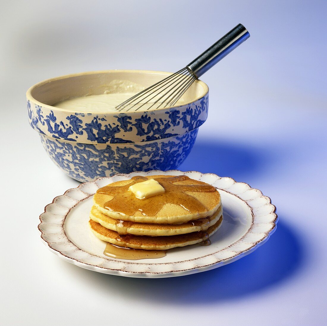 Gestapelte Pancakes mit Butter und Ahornsirup, Teig in Schüssel