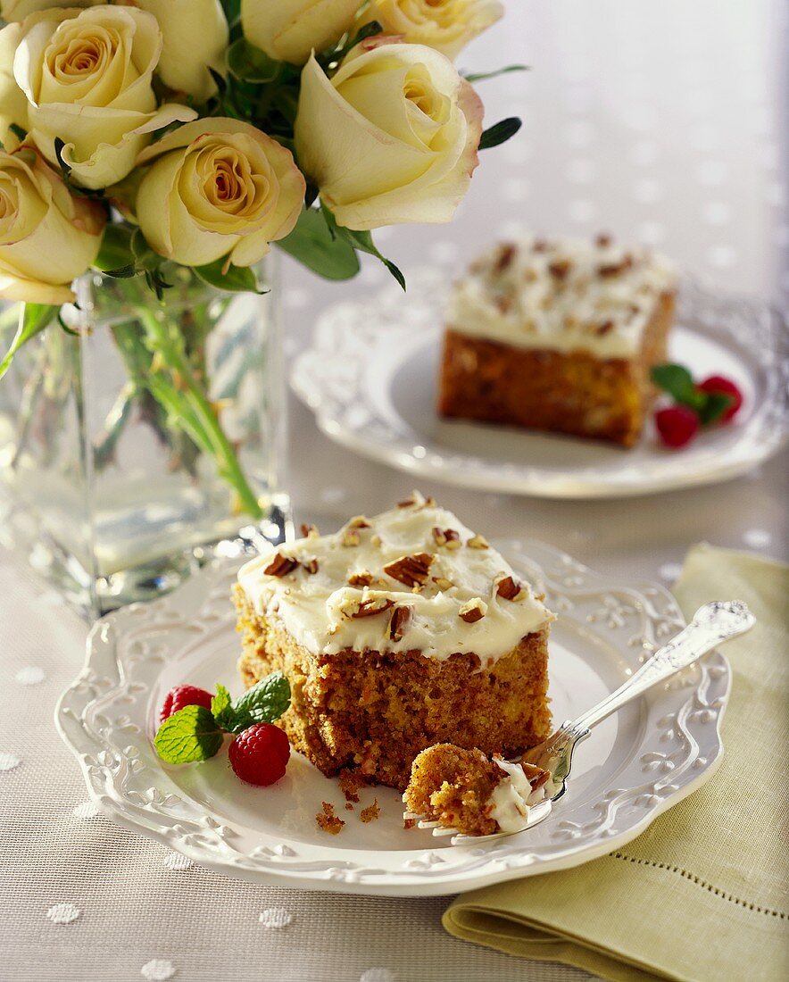 Stück Möhrenkuchen mit gehackten Mandeln; gelbe Rosen