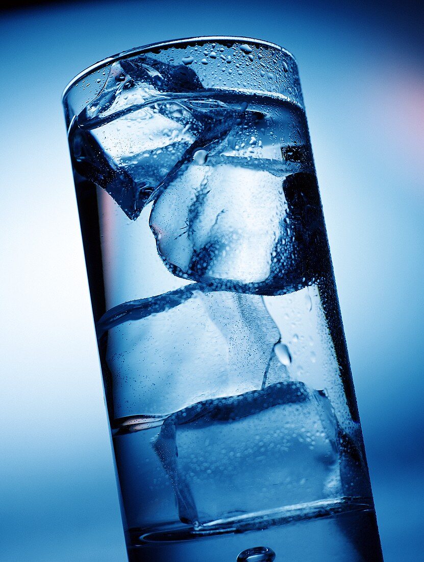 Glas Wasser mit Eiswürfeln in blauem Licht