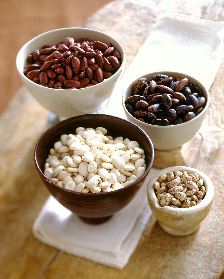 Four types of dried beans in ceramic bowls