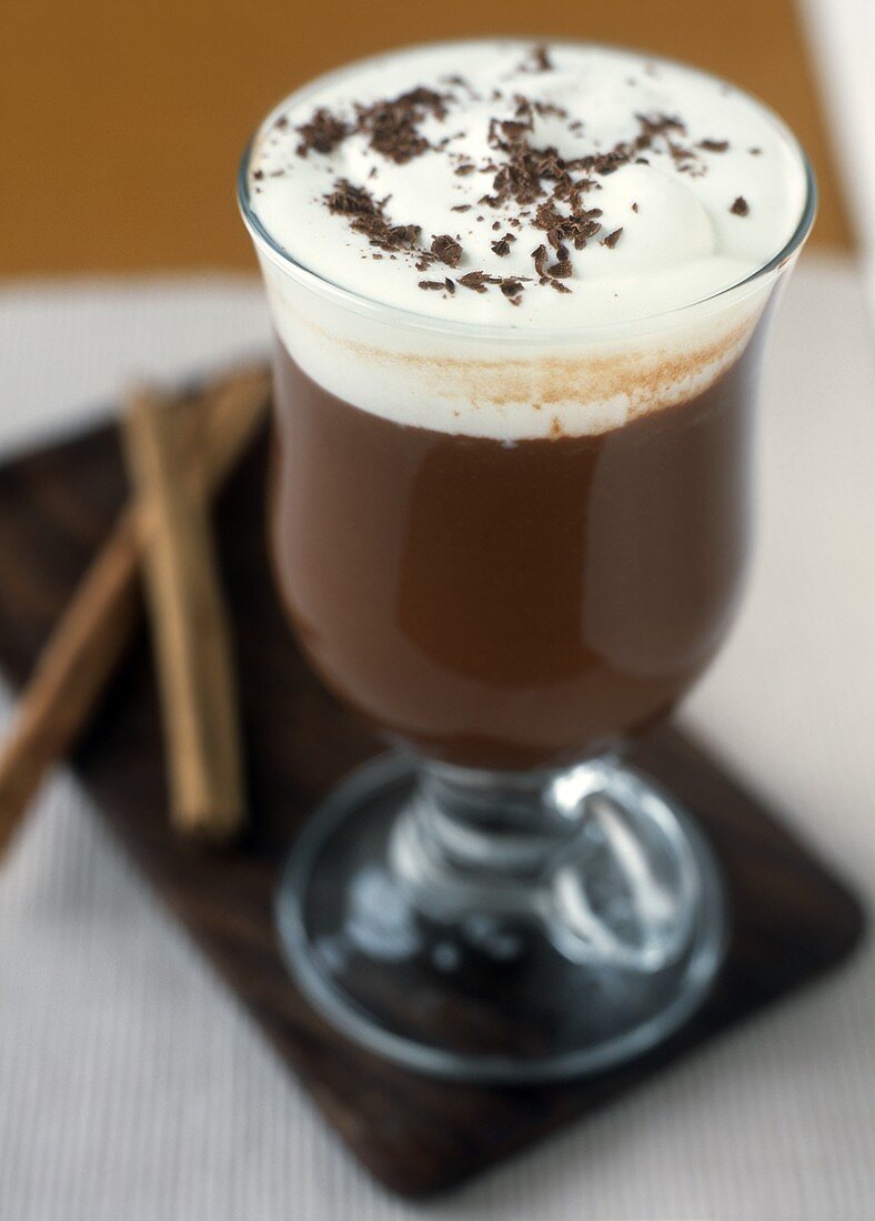 Hot chocolate with cream in glass; cinnamon sticks