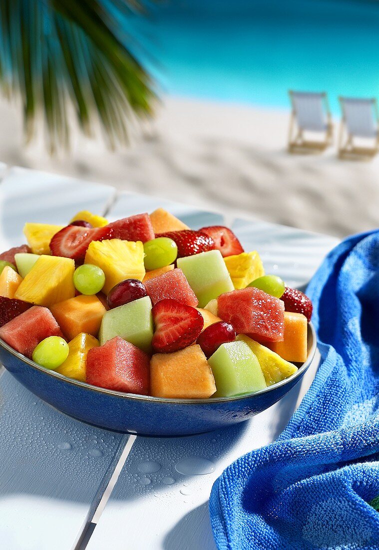 Bowl of fruit salad on table by sea