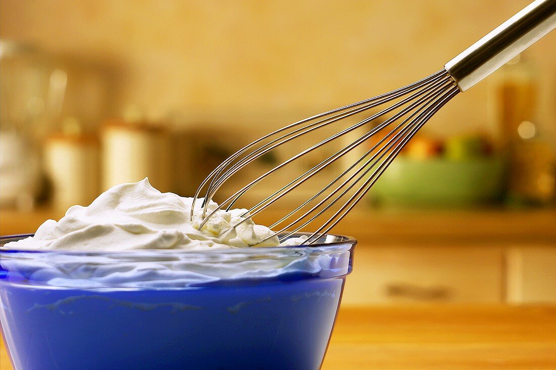 Bowl of whipped cream with whisk