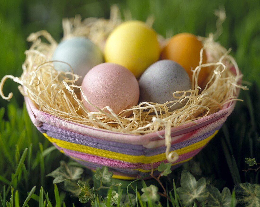 Colorful Easter Basket with Eggs in the Grass