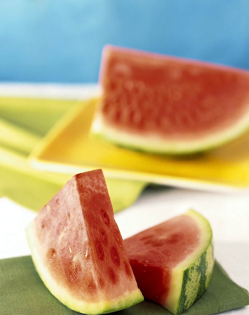 Seedless wedges of watermelon in front of half a watermelon