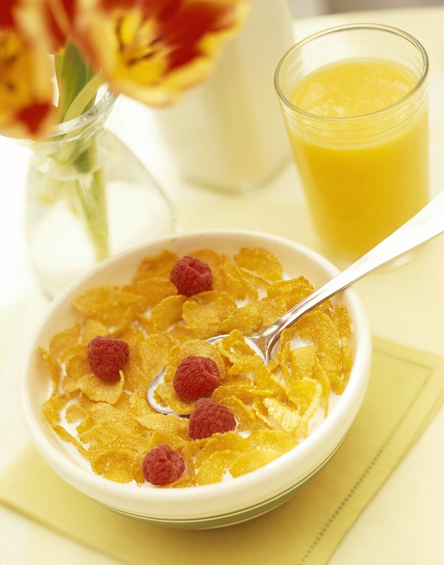Cornflakes with raspberries; glass of orange juice