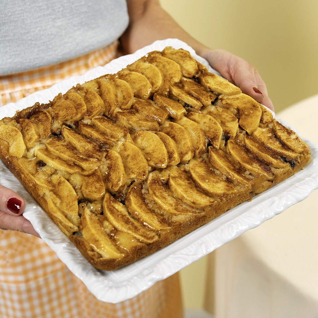Woman serving tray of freshly baked apple cake
