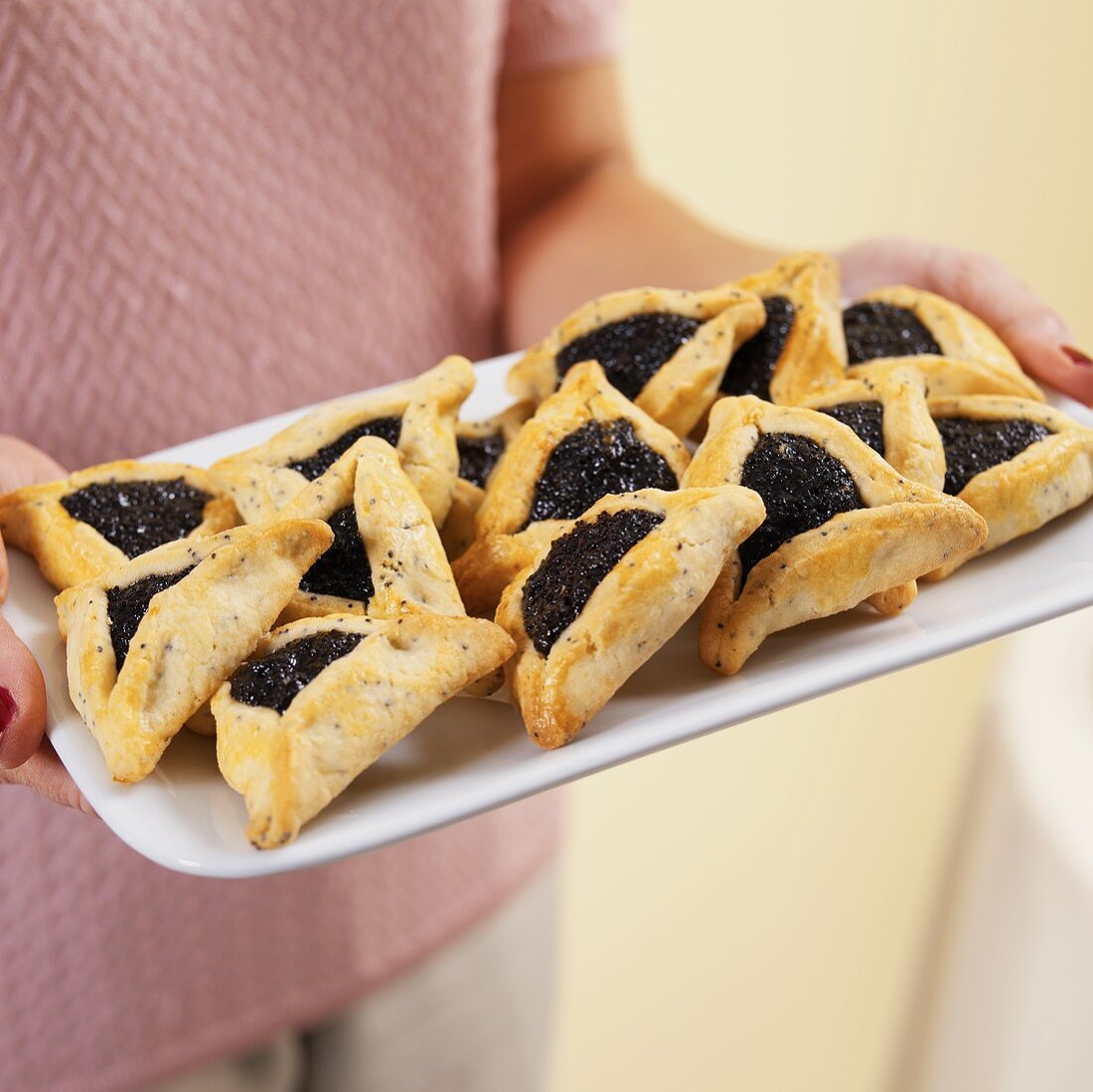 A person holding a tray of poppyseed turnovers
