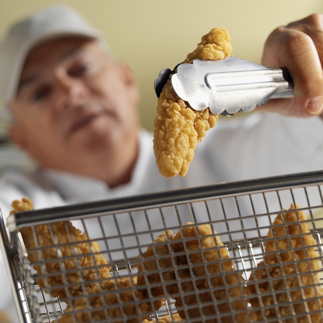 Chef taking chicken nugget out of frying basket