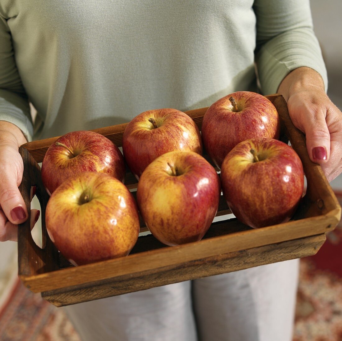 A Woman Holding a Wooden Tray with Fuji Apples