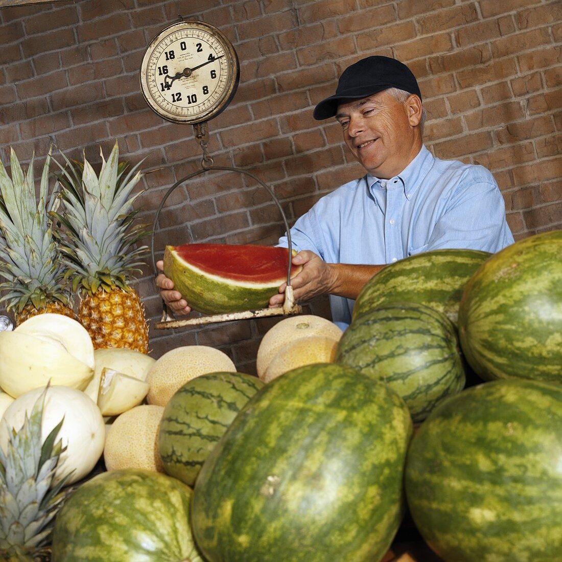 Mann wiegt Wassermelone am Marktstand