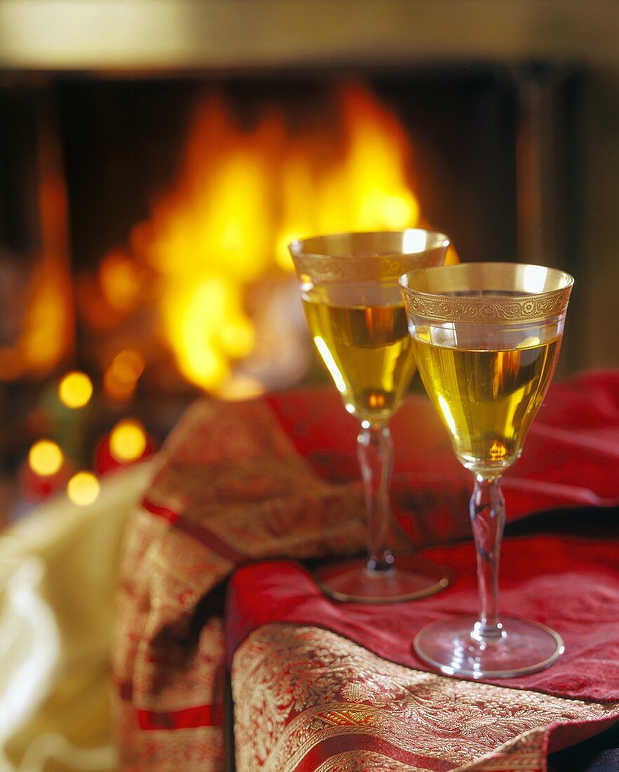 Two Glasses of White Wine Next to a Fireplace
