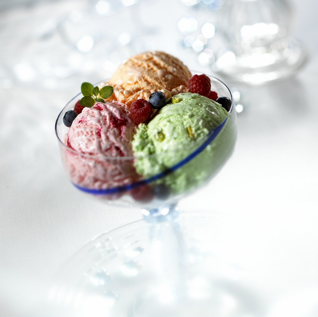 Scoops of pistachio, raspberry & orange ice cream in glass bowl