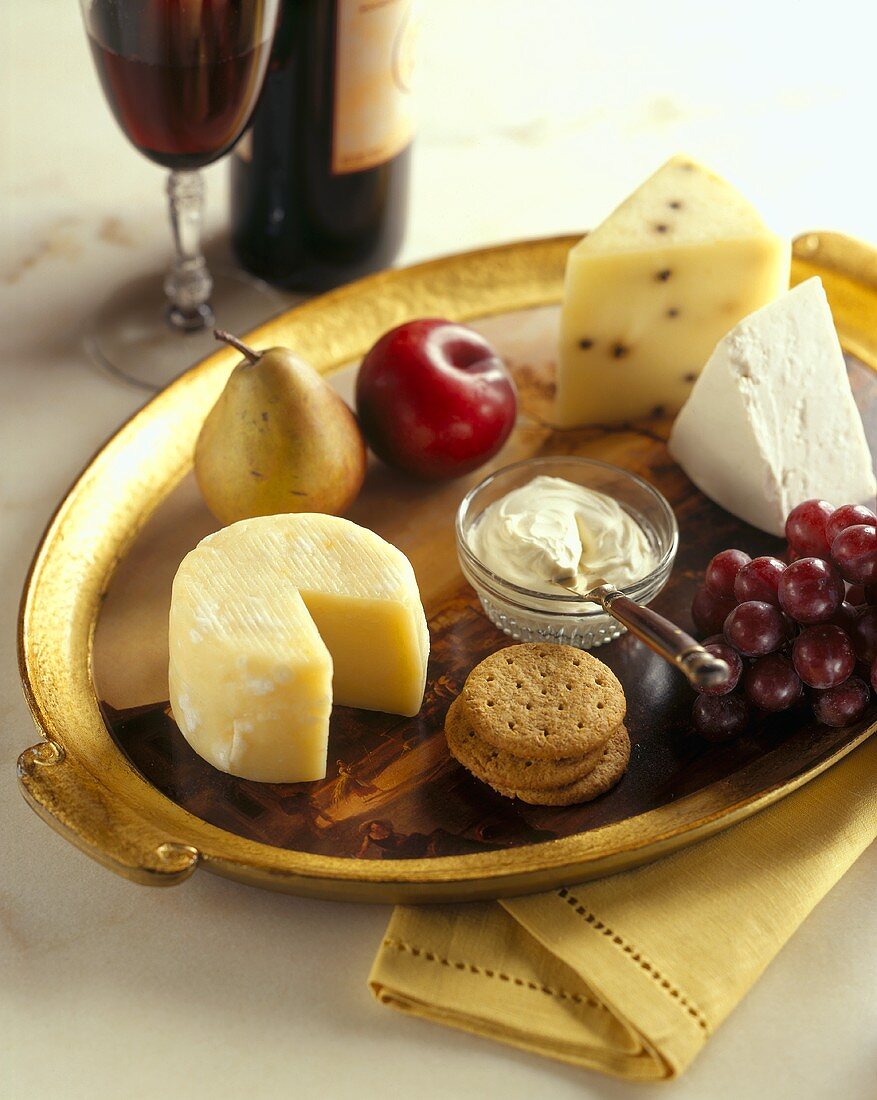 Verschiedene Käsesorten mit Obst, Crackern und Rotwein