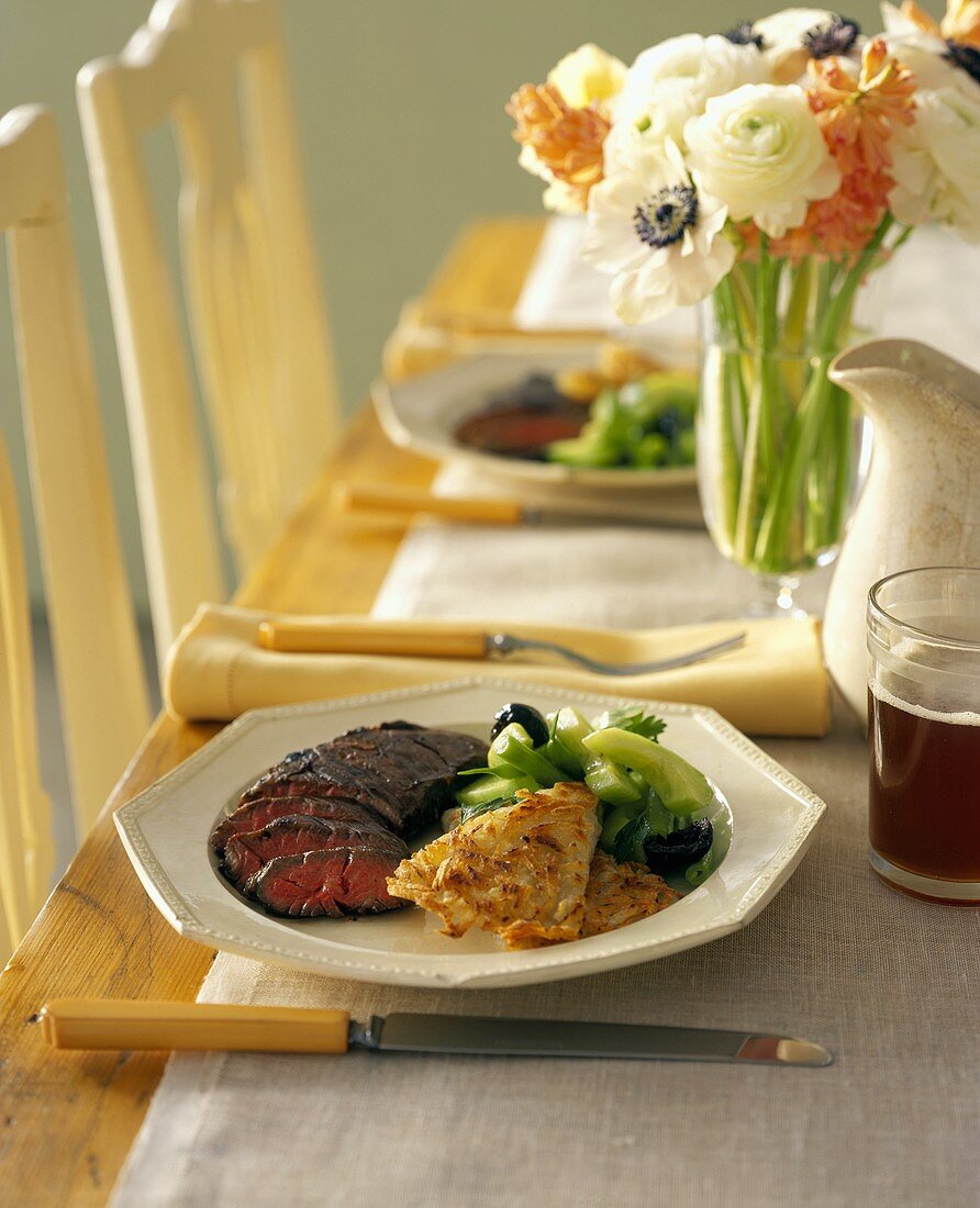 Rindersteak mit Latkas und Gurkensalat auf gedecktem Tisch
