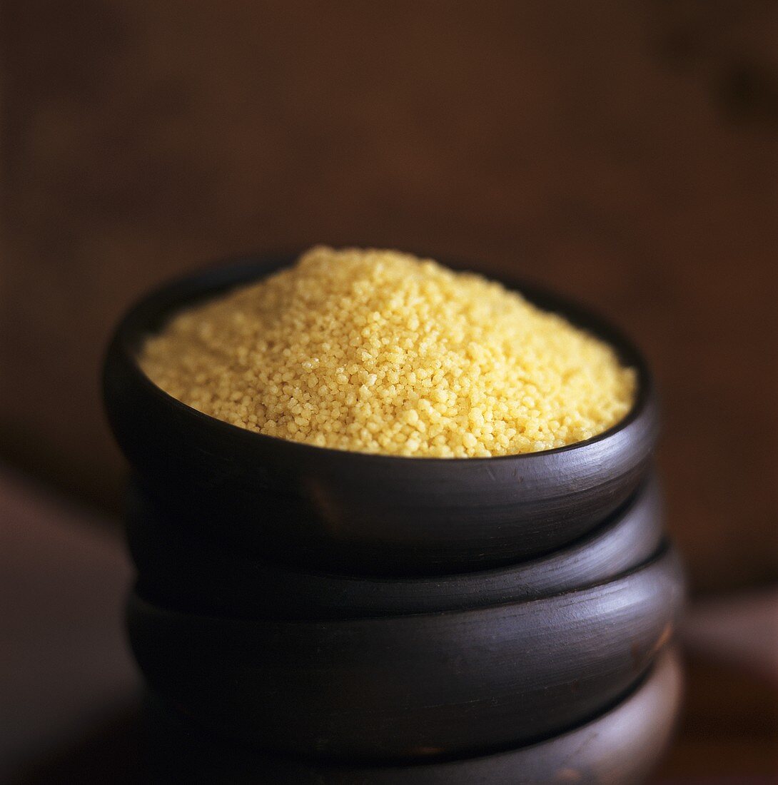 Couscous in wooden bowl on pile of bowls 