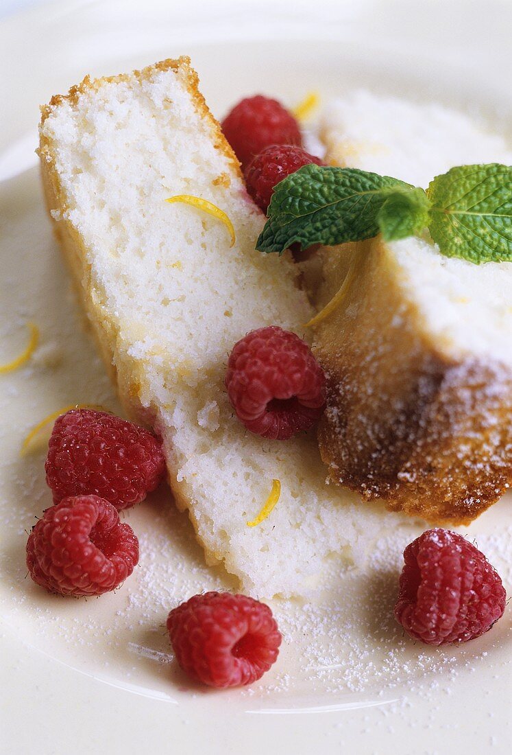 Two pieces of sponge cake with raspberries and mint