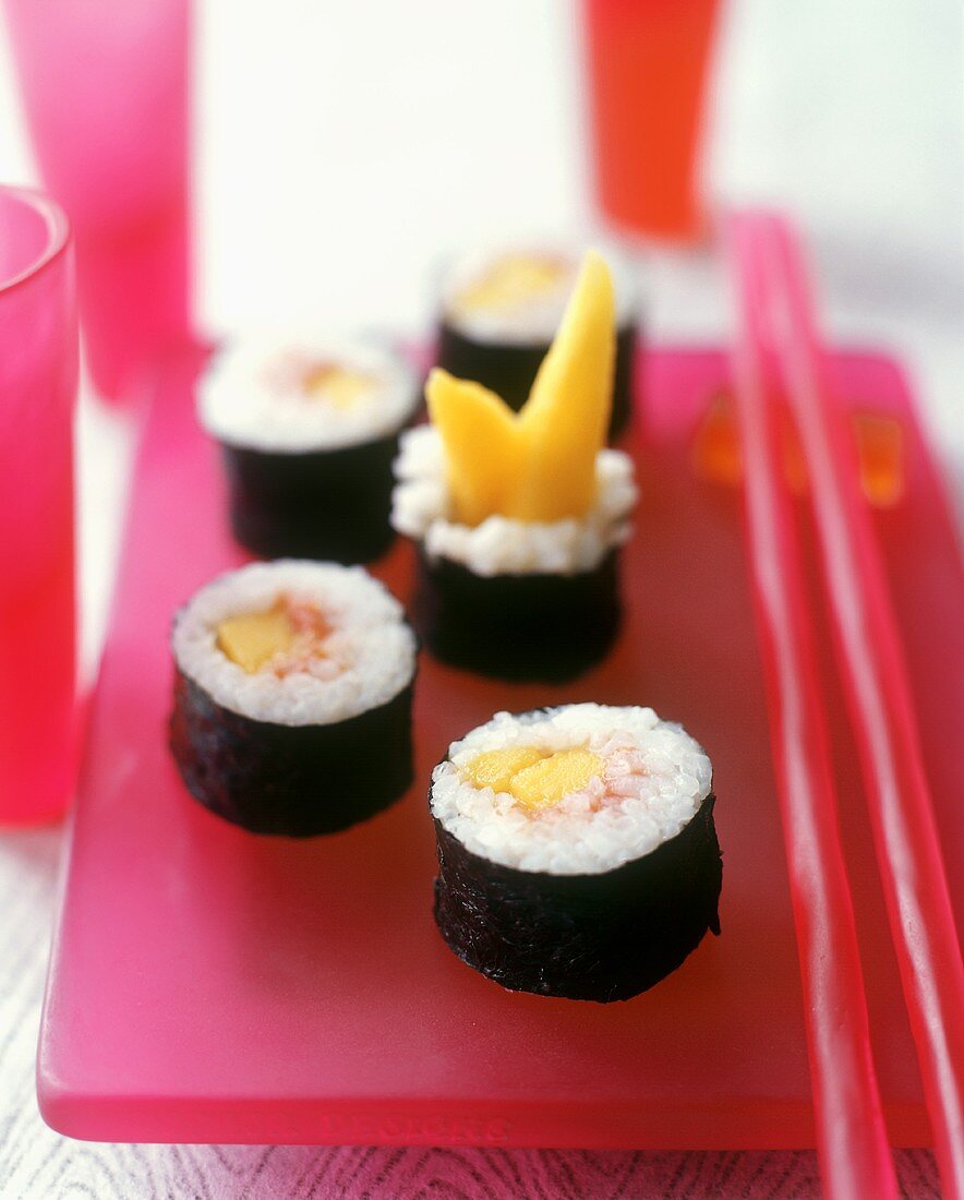 Maki-Sushi mit Mango auf rosa Platte