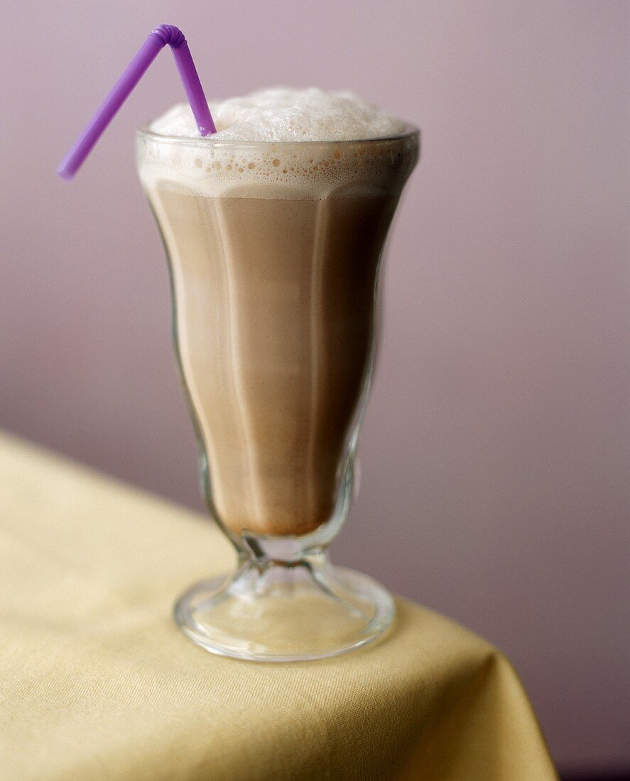Schokoladenmilch im Glas mit lila Strohhalm