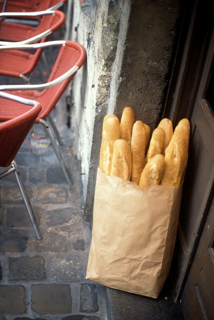 Frisch gebackene Baguettes in Papiertüte vor Tür eines Cafes