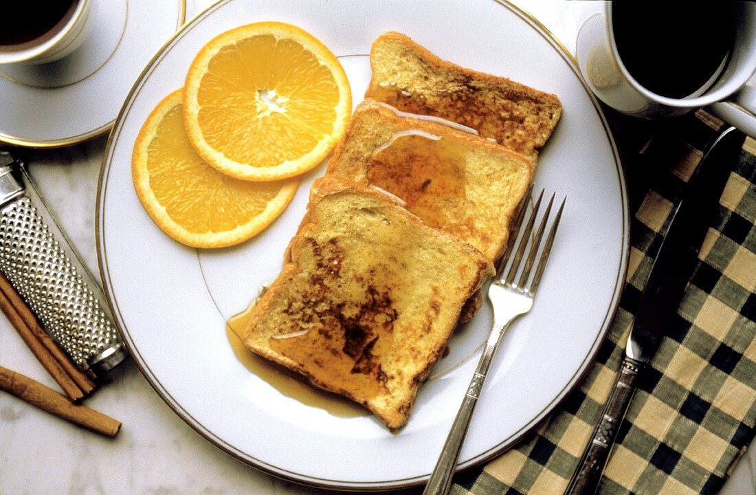 Drei Scheiben Toastbrot mit Sirup, Orangenscheiben auf Teller