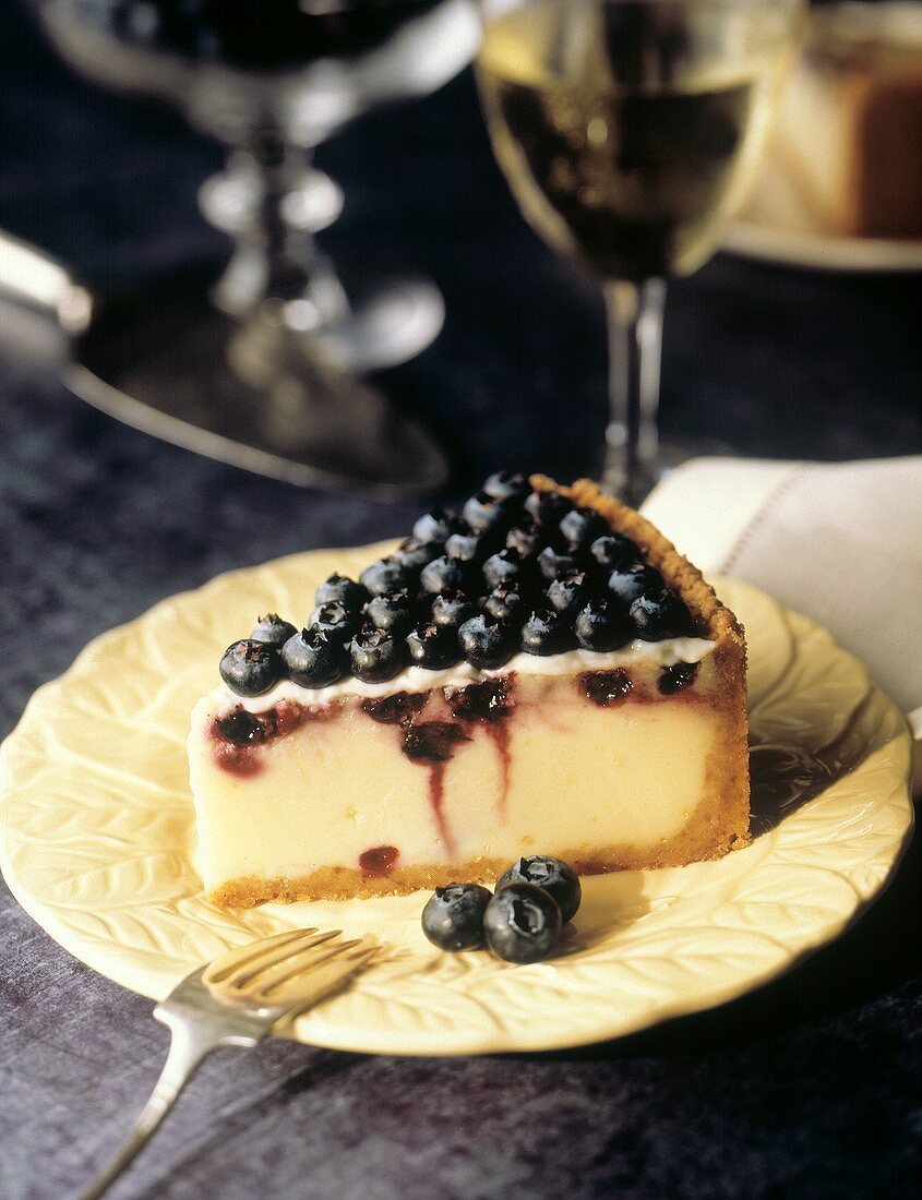 Ein Stück Zitronenkäsekuchen mit Heidelbeeren auf Teller