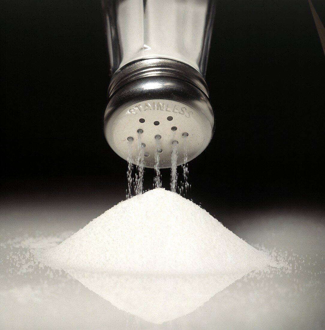 Salz rieselt aus Salzstreuer auf ein Häufchen Salz