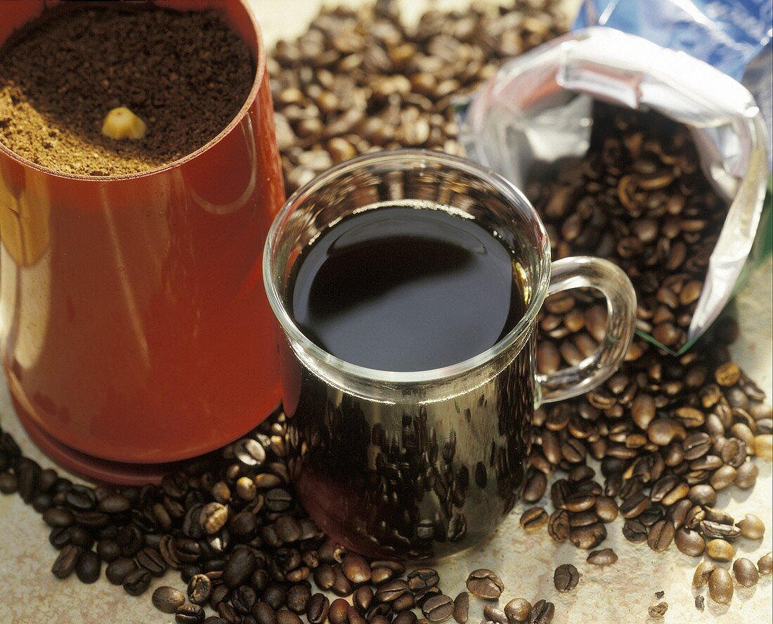 Kaffee in Glastasse, Kaffeebohnen und Kaffeemühle