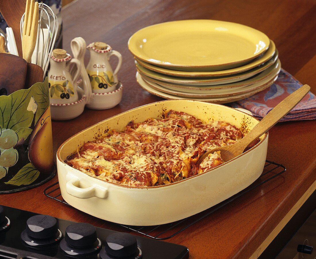 Baked Stuffed Shells in a Dish with a Wooden Spoon