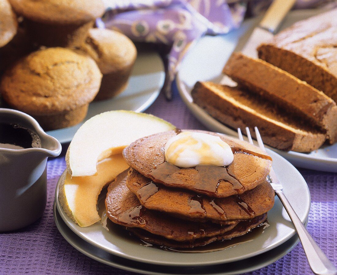 Ein Stapel Pancakes mit Butter und Ahornsirup; Muffins