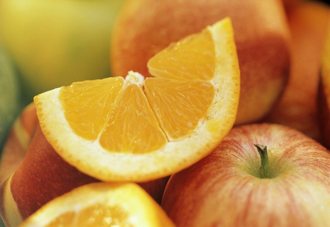 Ein Orangenschnitz auf roten Äpfeln & Orange