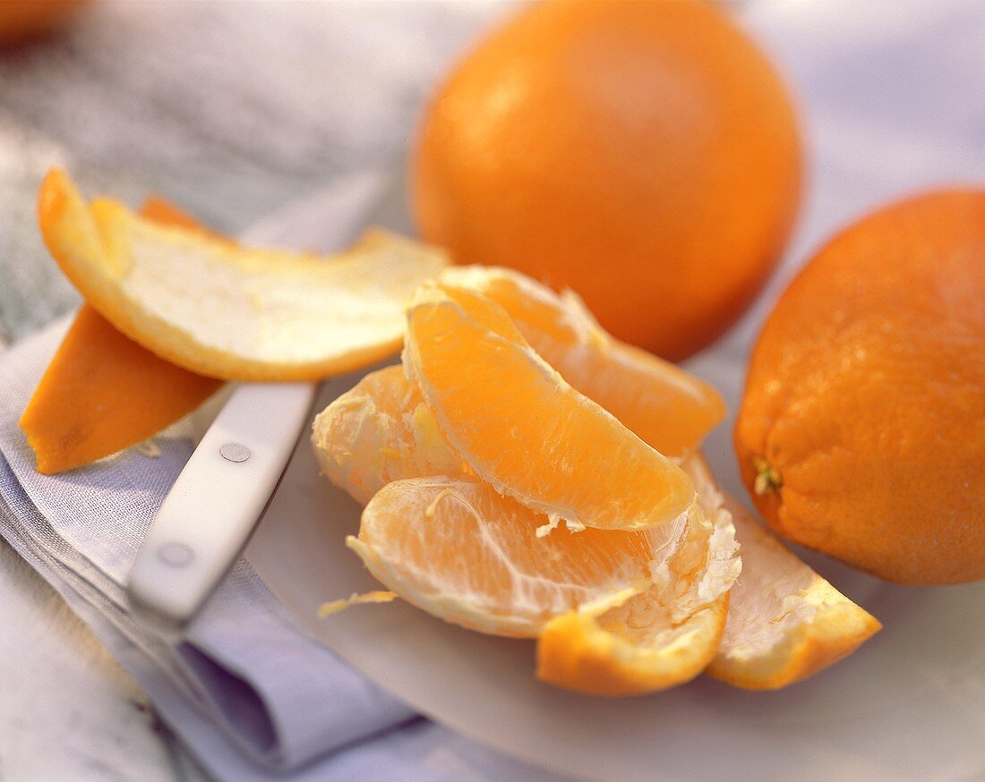 Orangenspalten, geschält, Orangenschale und ganze Orangen