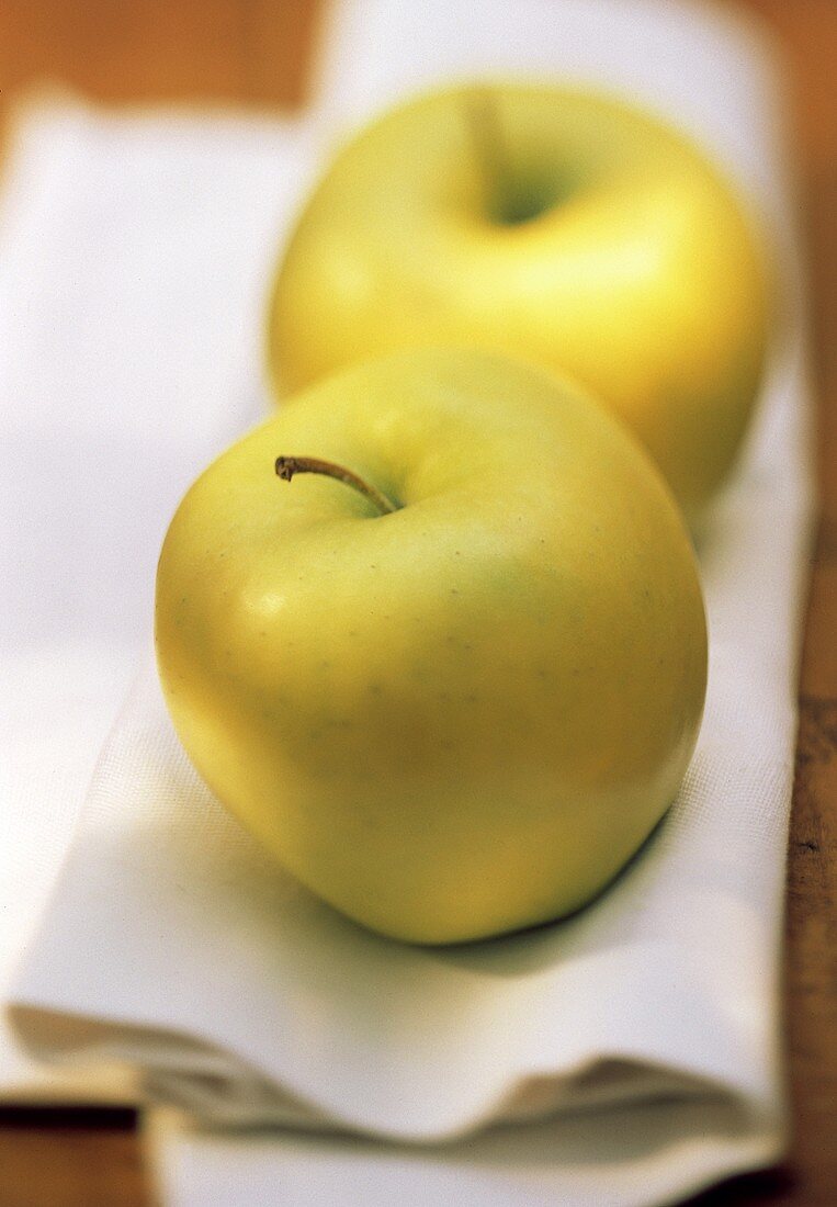 Zwei Golden Delicious Äpfel auf weißem Tuch