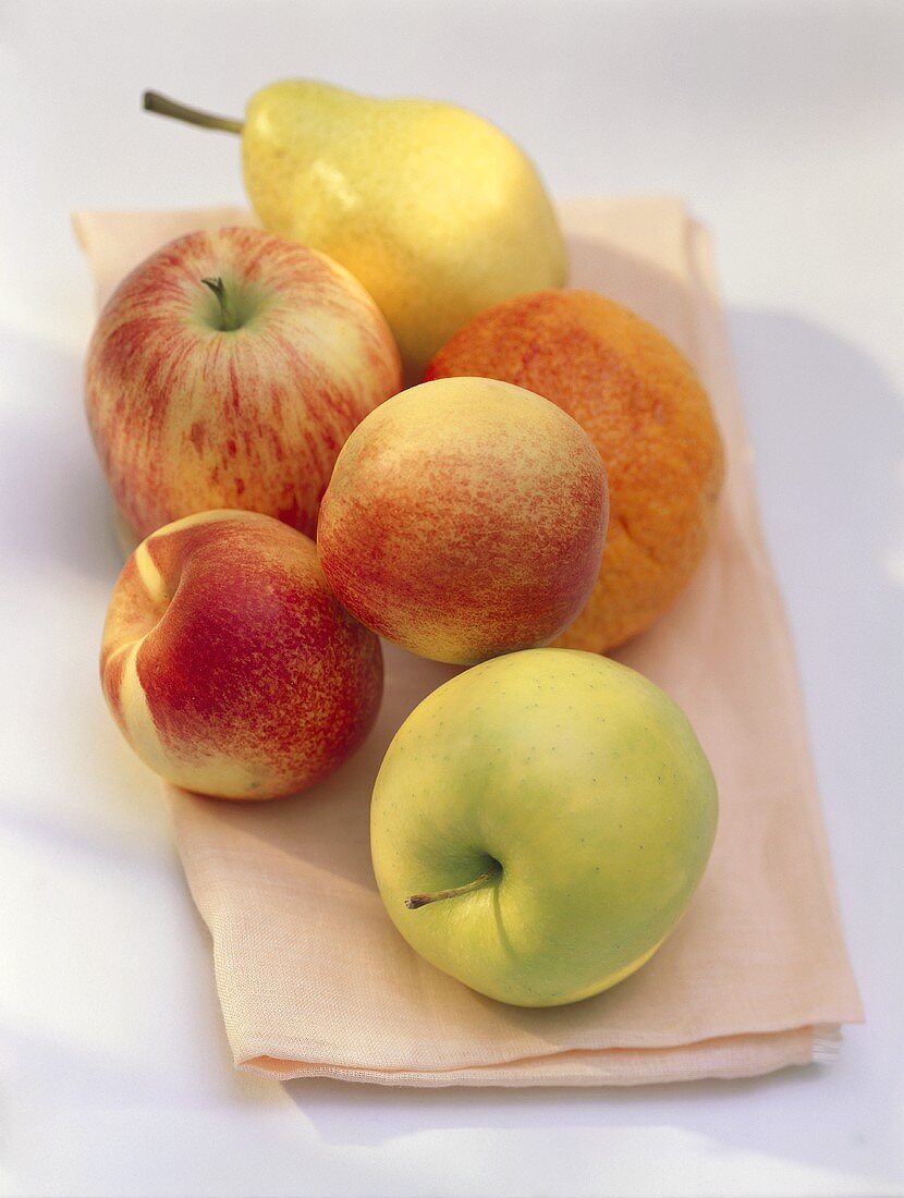 Verschiedene Früchte (Äpfel, Pfirsiche, Birne) auf Tuch