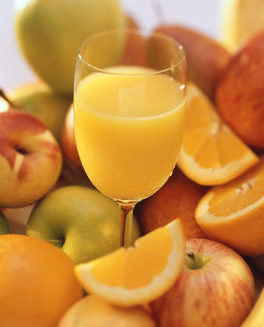 A Glass of Orange Juice in The Center of Assorted Fruit