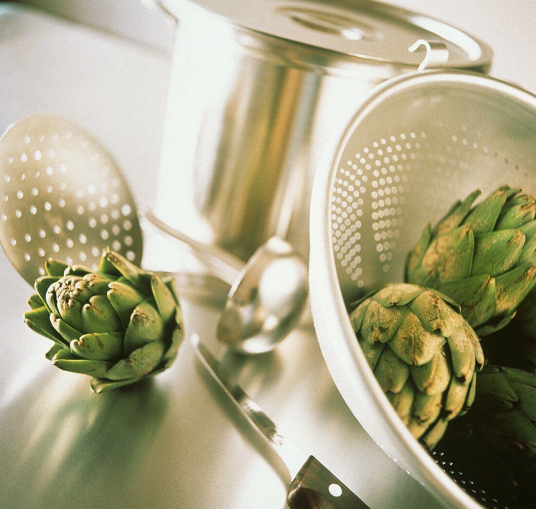 Artichokes in and Beside a Strainer; Kitchen Utensils