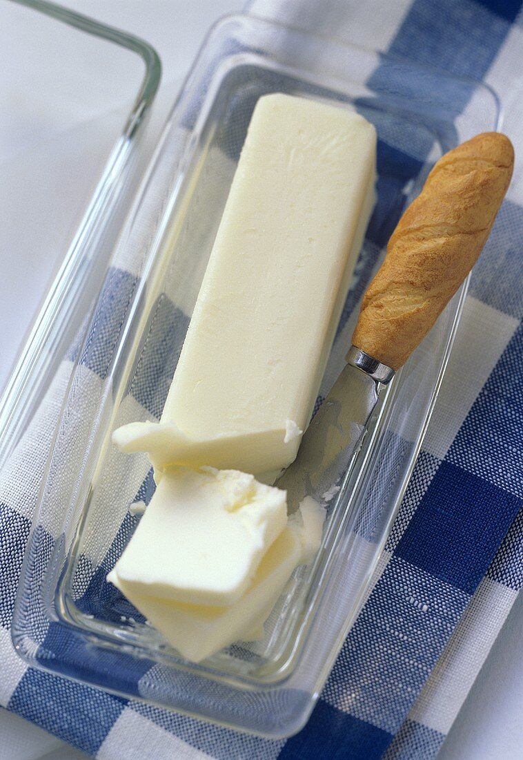 Butter, teilweise in Scheiben geschnitten, auf Glasbutterdose