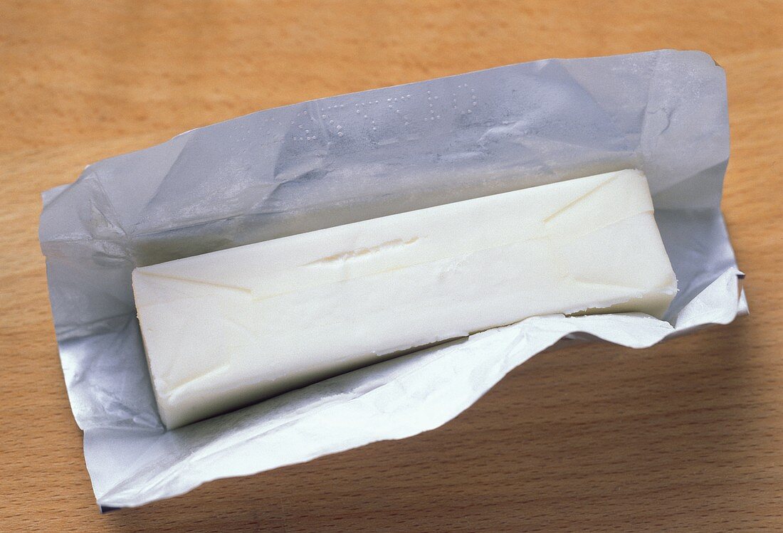 Ein Stück Butter auf geöffnetem Verpackungspapier