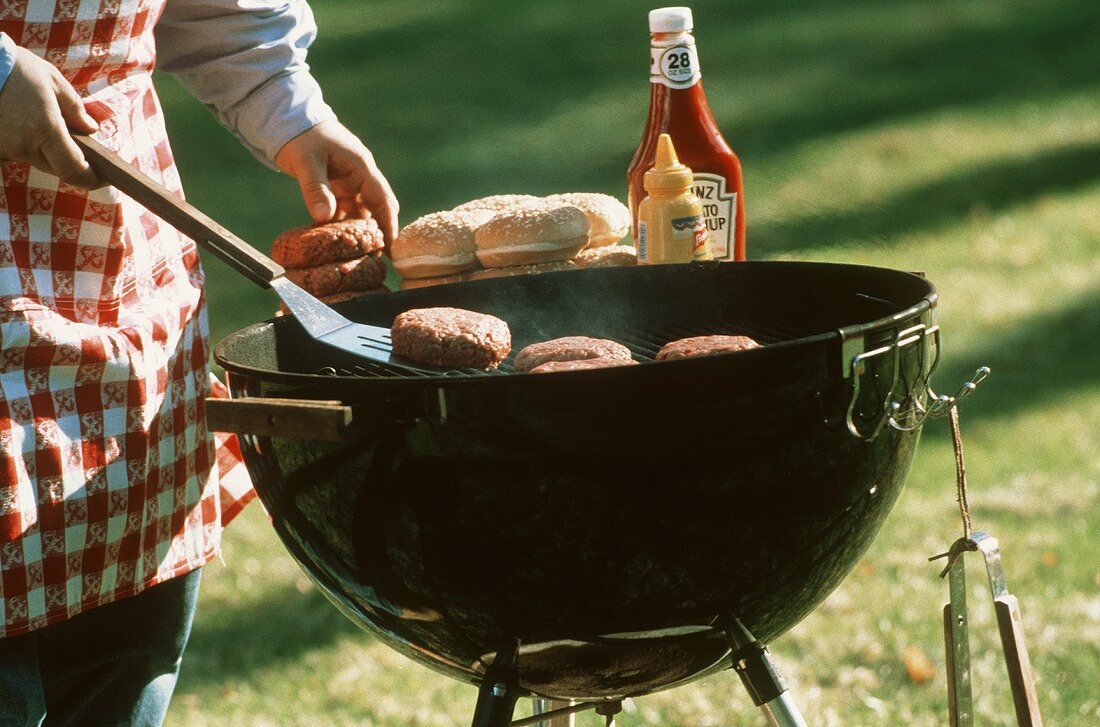 Koch grillt Frikadellen für Hamburger im Freien