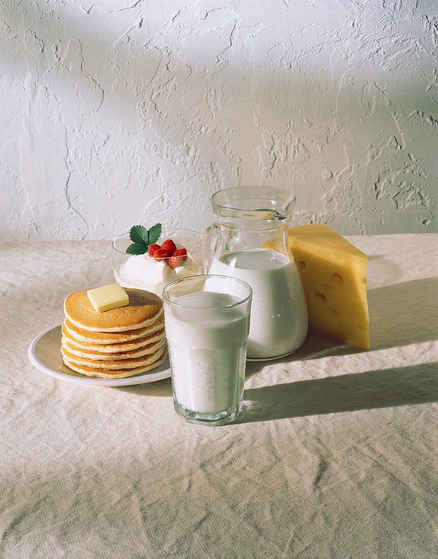 Milch, Joghurt, ein Stück Käse und Pancakes mit Butter