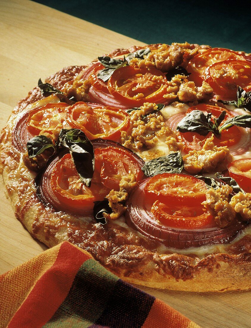 Pizza mit Wurst, Tomaten, Zwiebeln & Basilikum