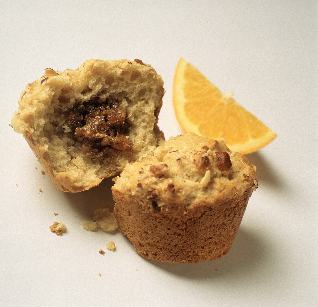 Muffin mit Feigenfüllung, halbiert, und ein Orangenschnitz