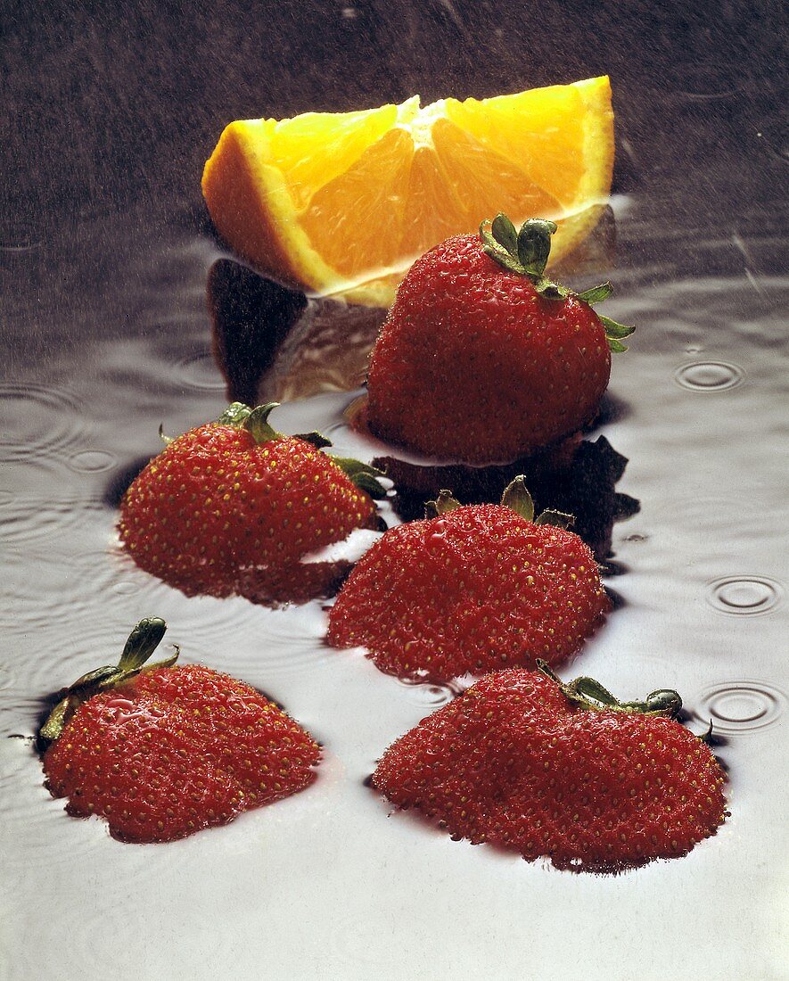 Erdbeeren und Orangenschnitz im Wasser