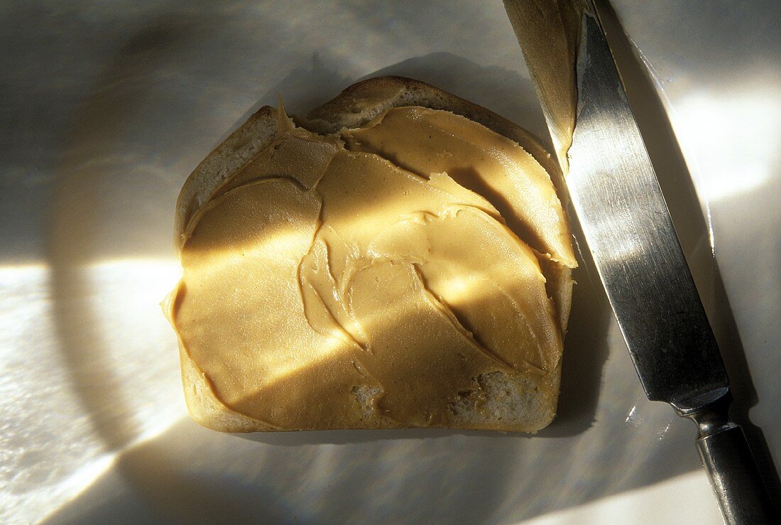 Weissbrotscheibe mit Erdnussbutter bestrichen und Messer