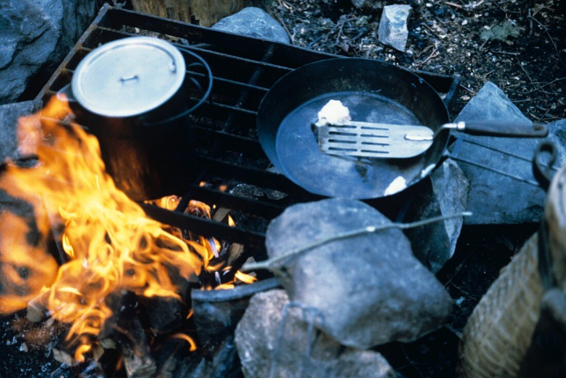 Pfanne mit Butter & Wasserkessel auf Campingfeuer