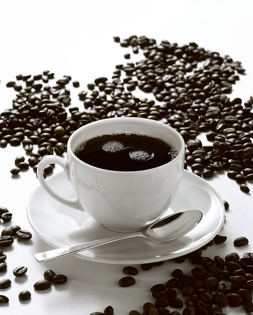 Ein Tasse Kaffee umgeben von Kaffeebohnen