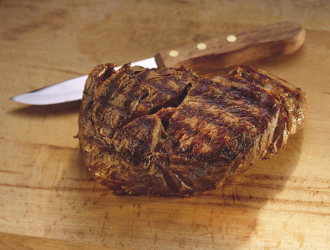Gegrilltes Ribeye Steak mit Messer auf Schneidebrett