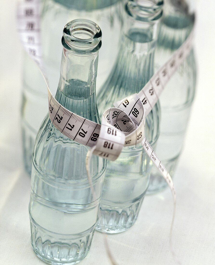 Einige Wasserflaschen mit einem Massband