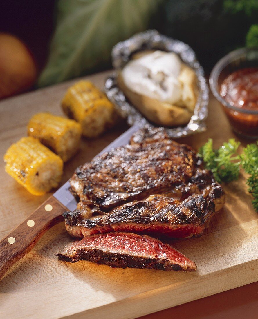 Partially Sliced Rib Eye Steak with Corn on the Cob